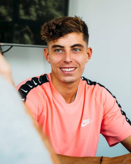 Kai Havertz in a orange t-shirt poses a picture.